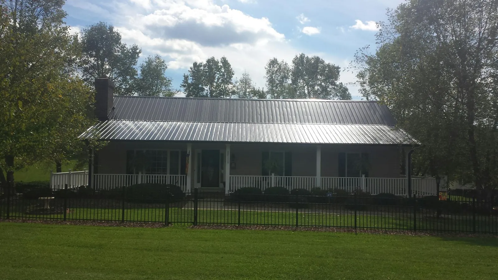 Gray metal roof on a brick ranch with a full width front porch — Gutter Guard Installation work by our crew in Blackwell