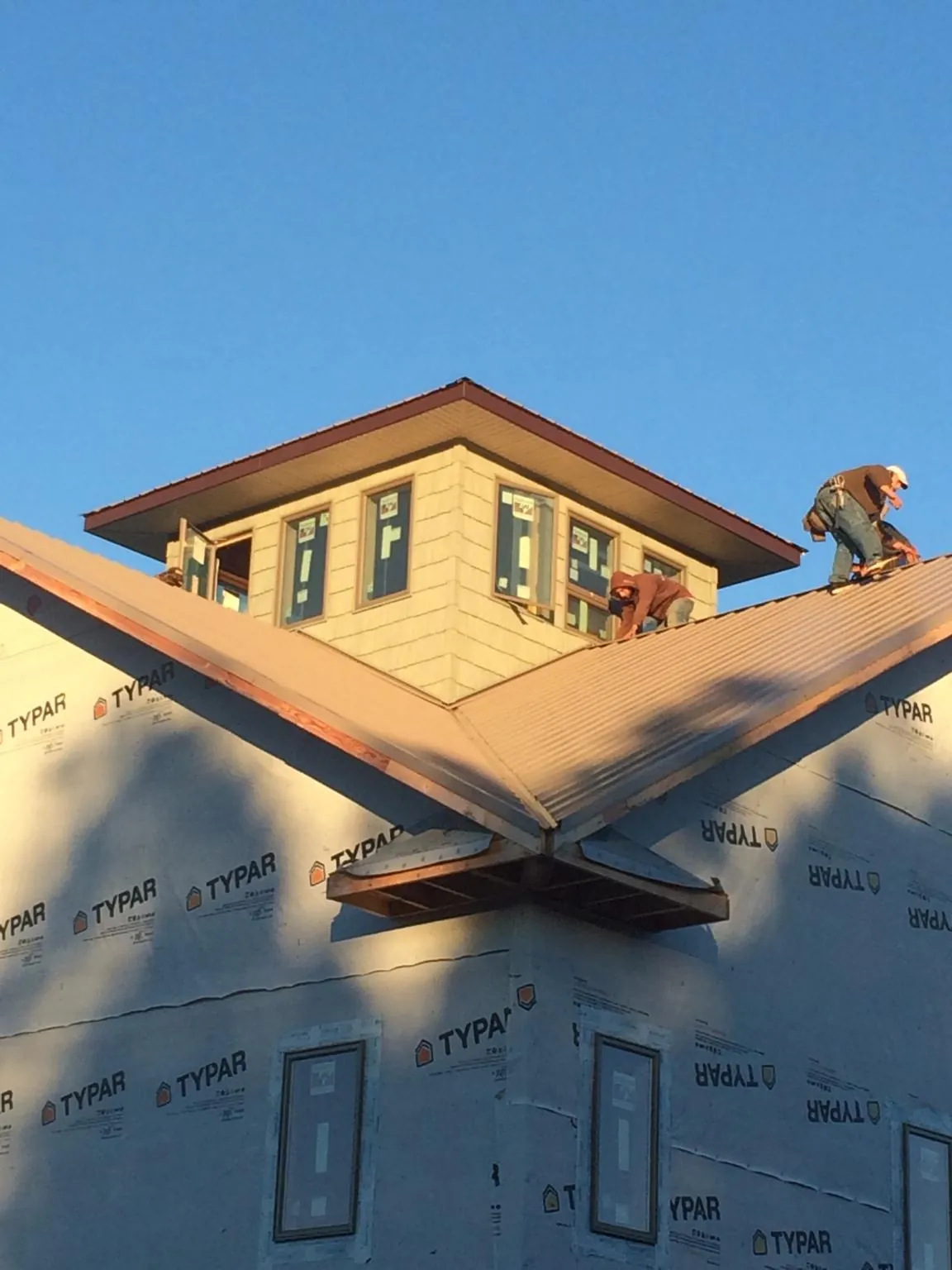 Roofers working around a rooftop cupola on a new metal roof at sunset — Roof Waterproofing in Blackwell by Roofing Brothers